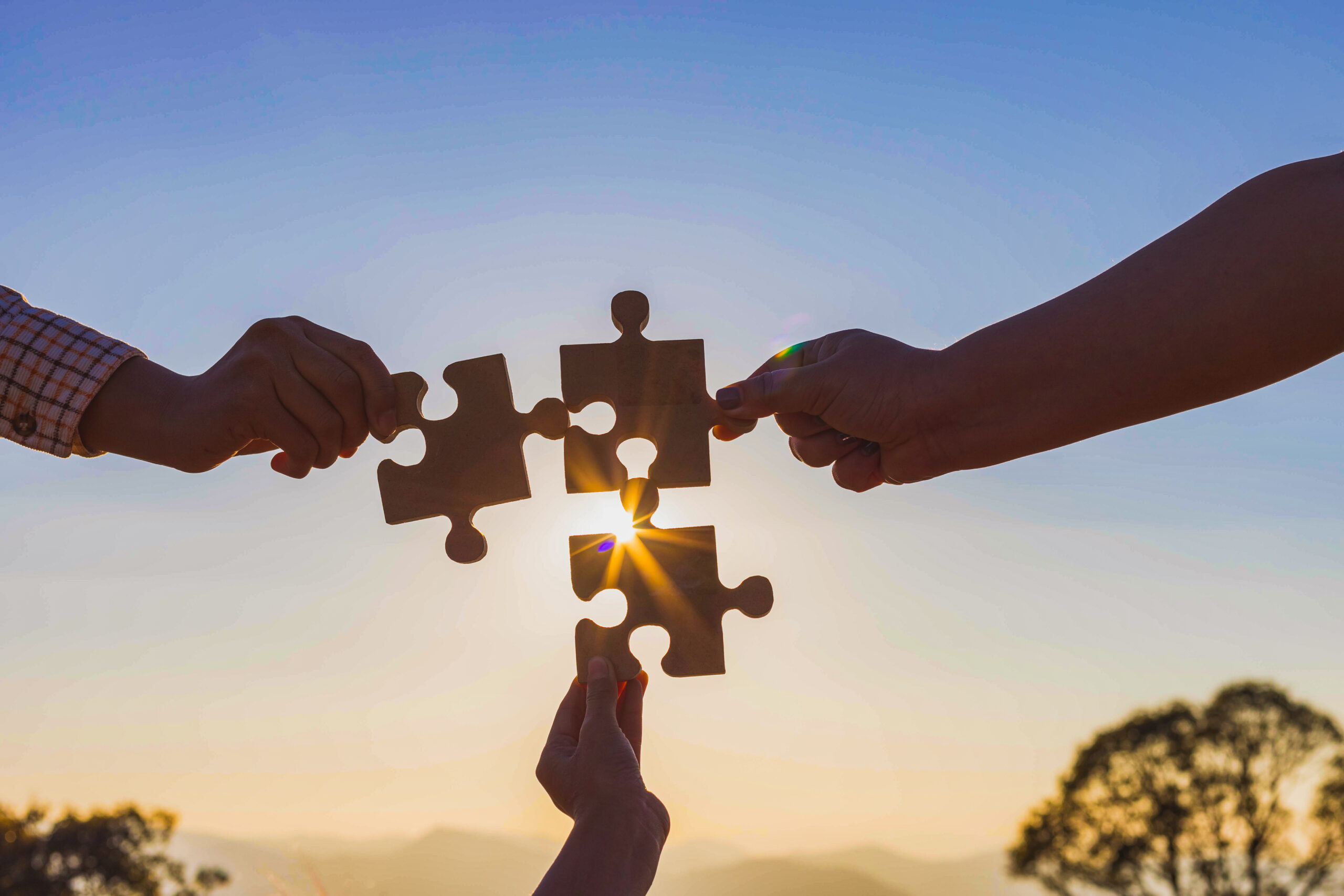 Human hands holding jigsaw puzzle at sunset background.team work and success and strategy concept.