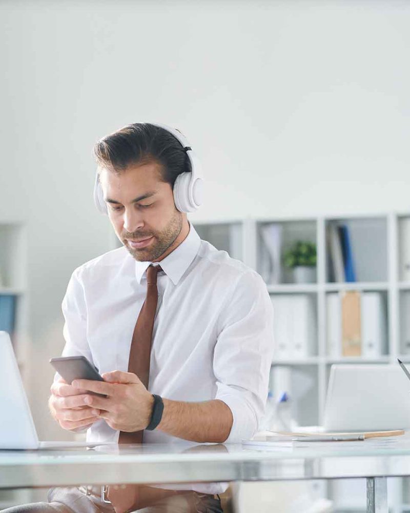 young-elegant-man-in-headphones-scrolling-in-smart-SPXKMZU.jpg